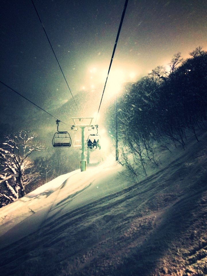二世古夜間吊椅纜車在落雪中緩緩爬升,兩旁是掛滿新雪的樹林